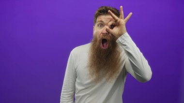 Mor stüdyoda uzun sakallı, beyaz tişörtlü bir adam göz çevresine imza atıyor..
