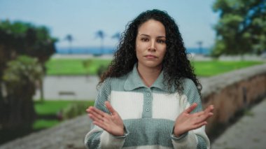 Uzak bir okyanus manzaralı parkta sıradan çizgili bir süveterle duran bir kadın tefekküre daldığını ifade ediyor..