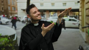 Sokak jestleri yapan rahip kılığındaki genç adam gülümserken ve arabalarla ve binalarla çevriliyken şehir manzarası ve dini bir tema izlenimi veriyor..