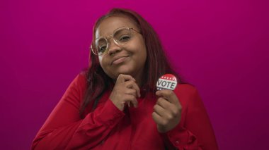 Gözlük takan kadınlar stüdyoda pembe arka planda oy vermek için işaret ediyorlar; vatandaşlık görevi yetkileri.