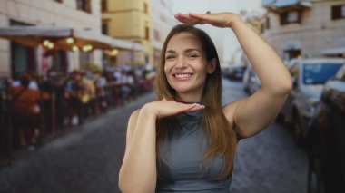 Meşgul şehir caddesinde gülümseyen kadınlar, park halindeki arabalar ve kaldırım kafeleri ile sıralanmış olarak ellerini çerçevelediler; neşeli neşe.