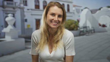 Açık havada gülümseyen bir kadın. Parlak şehir sokak ortamında. Sıradan moda tarzı ve güneşli bir atmosferi var..