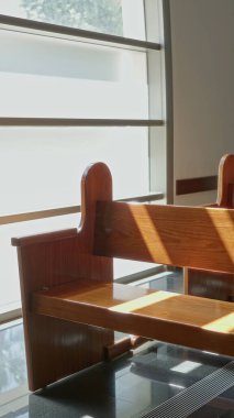 Kilisenin pencerelerinden süzülen güneş ışığı, kapalı alandaki boş ahşap sıraları aydınlatır. Mimari tasarım ve kutsal mekanın huzurlu atmosferini ön plana çıkarır..