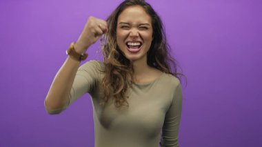 Gülümseyen enerjik İspanyol kadın, izole edilmiş parlak mor bir stüdyoda parmakları olan üç kişi sayıyor; heyecan..