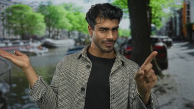 Genç Hispanik adam sokakta açık avuç içinin dışa dönük hareketlerine bakar; bağlantı sakinliği iç gözlem.