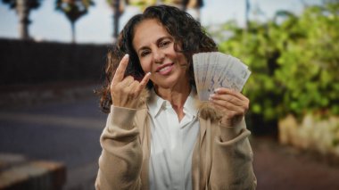 Şehir sokaklarında orta yaşlı bir kadın gururla taştan bir jestle Singapur dolarlarını sergiliyor..