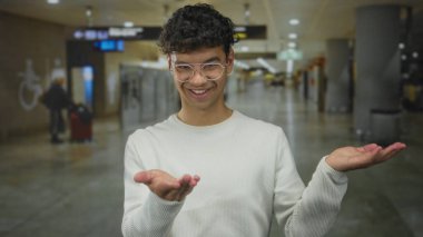 Havaalanı terminalinde uzun kollu beyaz gömlek ve gözlüklü bir adam avuçlarını açık tutuyor..