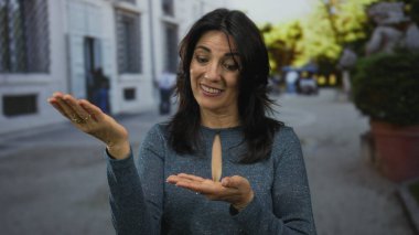 Güneş ışığı altında işlek sokak köşesinde açık avuç içleriyle kaşlarını kaldırmış bir kadın, açıklık..