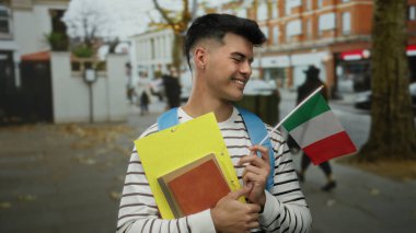Elinde İtalyan bayrağı ve klasörleri olan genç bir adam şehir merkezinde kültürel gurur ve eğitim duygusunu iletiyor..