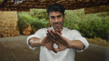 Genç İspanyol adam kaşlarını çatar ve beyaz bir gömlek içinde dışarı ahşap bir evin girişinde bakışlarını indirir; sessiz yansıma.