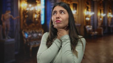 Genç İspanyol kadın, parlak avizelerin altında süslü müze galerisinin içinde boğazını sıkıyor..