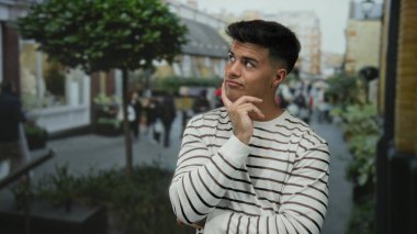 Şehir sokaklarında düşünceli bir ifadeyle gezen, çizgili süveter giyen, bulanık şehir geçmişi olan, düşüncelere dalan ve hareketli bir ortamda günlük tarzını sergileyen bir adam..