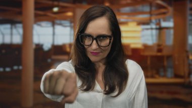 Genç İspanyol kadın otel resepsiyon masasının yakınındaki kameraya yumruk uzattı; güven güçlendirme kararlılığı.