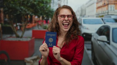 Kalabalık bir sokakta Kuzey Kore pasaportu gösteren bir kadın. Açık havada gülümseyerek kimlik belirleme ve seyahat kavramını ön plana çıkarıyor.