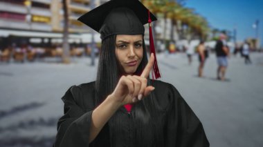 Mezuniyet şapkası takan İspanyol kadın, arka planda bulanık binalar olan bir şehir caddesinde fikir ayrılığı yaşıyor..