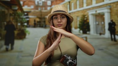 Şehir sokağında el kol hareketleri yapan genç bir turist. Gün ortasında boynunda kamerayla geziyor..