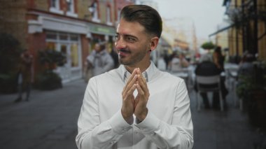 Adam açık hava tabloları ile tuğla mağaza önünde sokakta el çırpıyor parlak kentsel gün; beklenti.