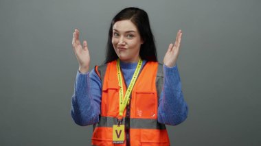 Gri arka planda elleri olan turuncu yelekli kadın toplum hizmeti ortamlarında gönüllülük ve iletişim tasvir ediyor.