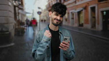 Kot ceketli genç adam şehir sokaklarında neşeli bir şekilde akıllı telefona bakıyor. Heyecanlı ve başarılı, bulanık şehir geçmişi olan..