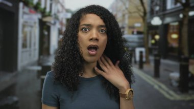 Dar ıslak sokakta boynuna yükseltilmiş el ve görünür tahta kol saatiyle dokunan kadın dükkanlar ve kalın zırhlarla dolu..