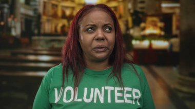 Yeşil gönüllü gömlekli kadın başını arkaya eğiyor, gözlerini kapatıyor ve eski kilise binasının içinde burnunu tutuyor..