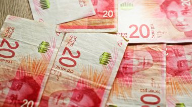 İsrail banknotları 20 şekel değerlerini gösteriyor, İsrail metni ve sembolleriyle belirgin kırmızı ve yeşil renkleri vurguluyor.