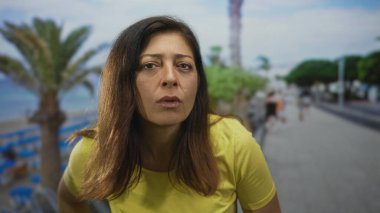 Sarı tişörtlü kadın dudakları ayrıldı ve kameraya odaklandı deniz kenarında bir sokakta öne eğilerek; tefekkür.