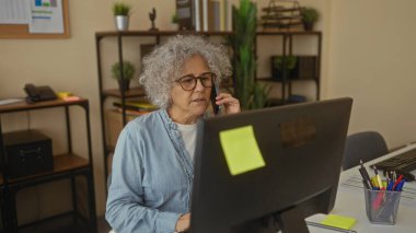 Modern ofiste telefonla konuşan kadın, iş iletişimi ve iş yeri dekorasyonuna odaklanan kitaplar ve bitkilerle çevrili..