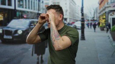 Dövmeli genç bir İspanyol, şehir sokaklarında elleri dürbünlü dürbünler kullanarak şehir ortamında neşeli ve ilginç ifadeler yakalıyor..