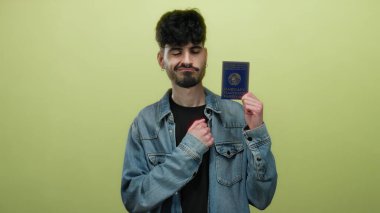 Belarus pasaportu taşıyan yakışıklı adam, izole edilmiş sarı duvarlara gururla bakıyor. Kimlik ve seyahat için hazır olduğunu gösteriyor..