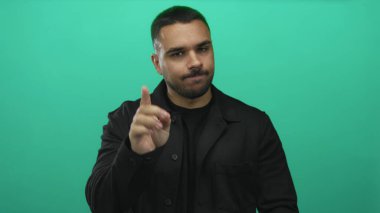 Canlı yeşil bir stüdyo duvarına karşı çapraz kollu siyah ceket giyen İspanyol genç adam reddedildi..