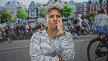 Şehir caddesinde bisiklet kiralama parkına karşı çenesinde dinlenen kısa gri saçlı kadın; tefekkür.