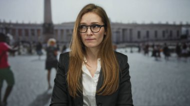 Vatikan Meydanı 'nda kaşlarını çatan gözlüklü kadın antik Aziz Peter sütununun altında; iç şüphe ve endişe.