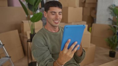 Karton kutular ve merdiven ile çevrili bir binada tablet ve tıklama ekranı tutan adam; memnuniyet.