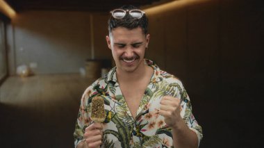 Genç adam tropikal bir tişört giyip otelde dondurma yemekten hoşlanıyor..