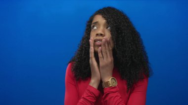 Mavi stüdyoda elleri sımsıkı bağlı Afrika kökenli Amerikalı bir kadın. Endişeli bir ifadeyle gözleri kapalı..