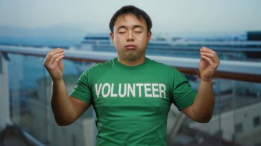 Bir yolcu gemisinde meditasyon yapan Asyalı bir adam açık havada gönüllü bir gömlek giyiyor, gözleri huzurlu bir şekilde kapalı seyahat ve hizmet ile farkındalığı karıştırıyor..
