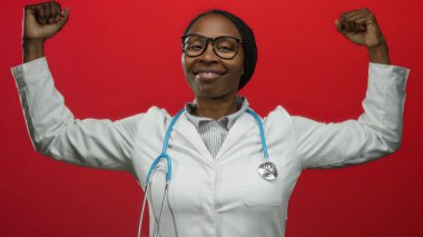 Steteskoplu, laboratuvar önlüğüyle gülümseyen kendine güvenen kadın doktor kırmızı arka plana karşı poz veriyor. Sağlık sektöründe güç ve güç gösteriyor.