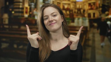 Genç beyaz kadın gotik kilise binasını işaret ediyor; dinginlik sadakat umudu.