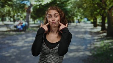 Parkta komik suratlar yapan genç bir kadın neşeli ve neşeli bir ifade sergiliyor..