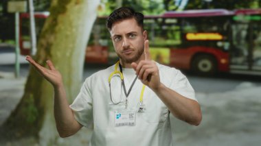 Beyaz önlüklü ve steteskoplu genç erkek doktor. Sokakta parmağıyla değil.
