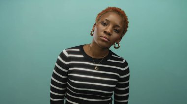 Kadın, kapalı gözleri ve çizgili üst daire küpeleri ile başını öne eğiyor; sakin iç gözlem.