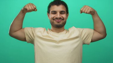 Parlak yeşil bir stüdyo alanında çıplak kollarını esneten ve yumruklarını sıkan İspanyol genç adam güven motivasyonu dayanıklılığını artırıyor..