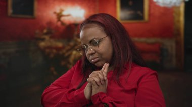 Kadın, dekoratif tabloların yanındaki müzede elleriyle parmak tabancası hareketi yapıyor..