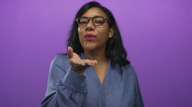 Stüdyoda mor arka planda el ele öpüşen gözlüklü ve mavi bluzlu bir kadın..