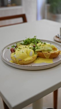 Lezzetli yumurtaların tadını çıkaran kişi, sıcak bir restoranda, içinde taze malzemeler ve parlak gün ışığı bulunan beyaz bir masanın üzerinde çatal ve bıçakla birlikte avakado ile birlikte..