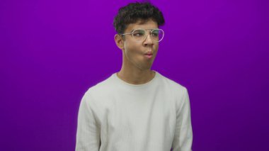 Mor stüdyoda, yuvarlak gözlüklü ve beyaz gömlekli İspanyol adam dudaklarını öne doğru uzattı..