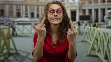 Kırmızı gömlekli kadın Aziz Peter Meydanı 'ndaki Vatikan' da el hareketi yapıyor. Bulanık insanlar ve arka planda mimari anlayışı açık havada tutumunu gösteriyor..