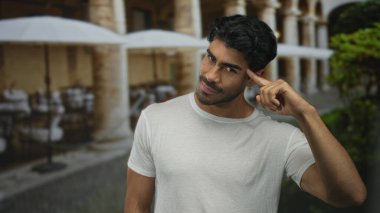 Lokanta terasında beyaz tişörtlü adam parmak ucundaydı. Yumuşak güneş ışığında inşa ediliyordu..