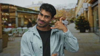 İspanyol adam açık hava restoranının terasında masaları ve sandalyeleri görünür, mutluluk bağlantıları olan bir jest yapıyor..